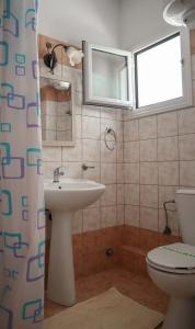 bagno con lavandino, servizi igienici e finestra di Spyridoula a Lourdata
