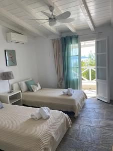 a bedroom with two beds and a ceiling fan at Villa Bounatsa with access to semi-private beach in Kanapitsa