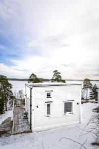 a small white house in the snow next to a lake at New lakehouse - amazing sea view and private pier! in Stockholm