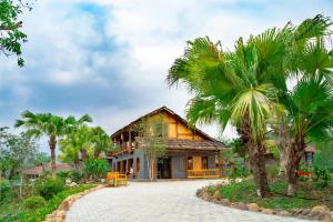 a house with palm trees in front of it at Mường Lò Retreat Nghia Lo in Yên Bái