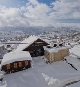 ארואד סוויטס Arwad suites في مجدل شمس: مبنى مغطى بالثلج مع مدينة في الخلفية