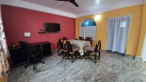 Zimmer mit einem Tisch und Stühlen sowie einem TV in der Unterkunft Tariang's Enclave Homestay in Shillong