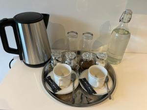 uma bandeja com chávenas e copos numa mesa com uma cafeteira em Chez Thomas 7 Route du Monde Ancien em Saint-Georges-dʼAunay