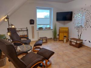 ein Wohnzimmer mit Stühlen und einem Flachbild-TV in der Unterkunft Trekvogels Utkiek in Dornum
