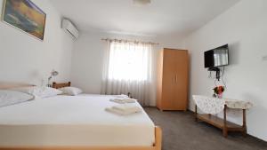 a bedroom with a white bed and a television at Apartment in nature in Bijela