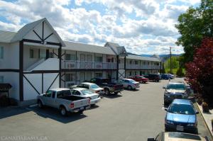 un estacionamiento con autos estacionados frente a un motel en Rosedale Motel, en Summerland