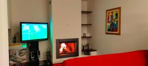 ein Wohnzimmer mit einem TV und einem Kamin in der Unterkunft L'OLIVO appartamento turistico in Lucignano
