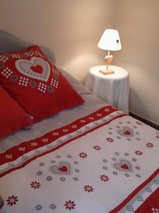 a bed with red pillows and a table with a lamp at Casa MARIA in Limone Piemonte