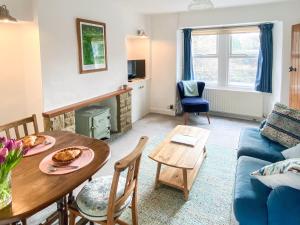 a living room with a table and a blue couch at Holme Cottage in Embsay
