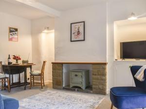 a living room with a fireplace and a tv at Holme Cottage in Embsay