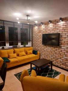 a living room with a couch and a tv on a brick wall at FRIENDS House in Gorzów Wielkopolski