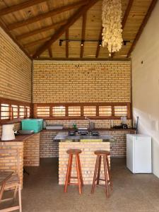 a kitchen with a counter and two stools in it at Bungalows Morro Do Chapeu Taiba in Taíba