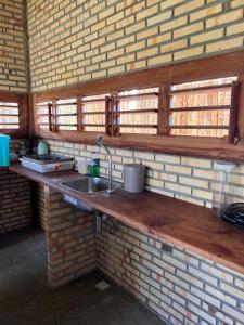 a kitchen with a sink and a brick wall at Bungalows Morro Do Chapeu Taiba in Taíba