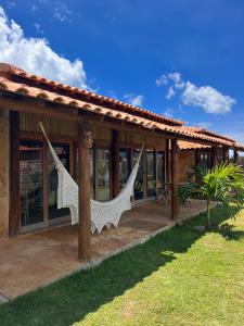 une maison avec une terrasse couverte dotée d'un hamac. dans l'établissement Bungalows Morro Do Chapeu Taiba, à Taíba