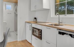 a white kitchen with a sink and a microwave at 2 Bedroom Beautiful Apartment In Vggerlse in Marielyst