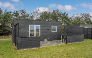 a black tiny house sitting on top of a field at 2 Bedroom Beautiful Apartment In Vggerlse in Marielyst