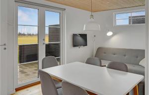 uma sala de jantar com uma mesa e cadeiras brancas e uma televisão em 2 Bedroom Beautiful Apartment In Vggerlse em Bøtø By
