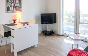 a living room with a television and a white desk with a table at 1 Bedroom Awesome Apartment In Gudhjem in Gudhjem