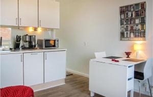 a kitchen with white cabinets and a table with a microwave at 1 Bedroom Awesome Apartment In Gudhjem in Gudhjem