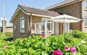 ein Haus mit einem Regenschirm und ein paar rosa Blumen in der Unterkunft Vrije Vogels in Bergen aan Zee