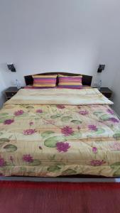 a large bed with a floral bedspread on it at JiNo Homestay in Khajurāho
