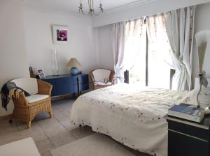 1 dormitorio con 1 cama, 1 silla y 1 ventana en appartement Nice , jardin et mer, en Niza