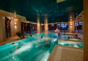 a large swimming pool in a building with people in it at Dworek Morski SPA & Wellness in Mielno