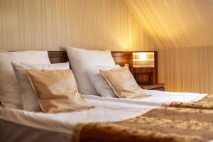 Schlafzimmer mit einem Bett mit weißer Bettwäsche und Kissen in der Unterkunft Dworek Morski SPA & Wellness in Mielno