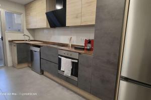 una cocina con electrodomésticos de acero inoxidable y armarios de madera en Este si ! en Benicàssim