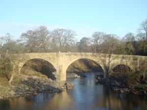 a bridge over a river with people walking on it at Rose Cottage in Tunstall +7 photos