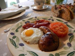 a plate of breakfast food with eggs sausage and tomatoes at Rose Cottage in Tunstall