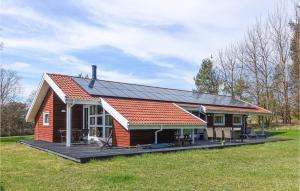 a small red house with a large deck in a field at Stunning Home In Aakirkeby With Wifi in Vester Sømarken