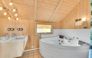 a bathroom with a large tub and a sink at Awesome Home In Hvide Sande With Sauna in Bjerregård