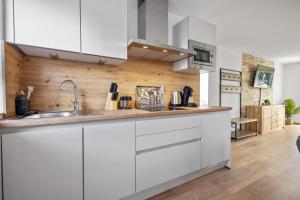 una cocina con armarios blancos y fregadero en Apartments Münchbach - near Europa-Park and Rulantica - Parking I Kitchen I WiFi, en Rust