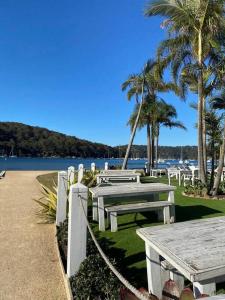 una fila di tavoli da picnic sulla spiaggia con palme di Travellers Retreat Bayview a Bay View