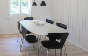 Gorgeous Home In Aakirkeby With Wifi في Vester Sømarken: طاولة غرفة طعام بيضاء مع كراسي سوداء