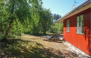 a red building with a bench next to a tree at Gorgeous Home In Aakirkeby With Wifi in Vester Sømarken