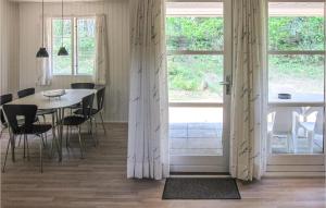 una sala da pranzo con tavolo, sedie e finestre di Gorgeous Home In Aakirkeby With Wifi a Vester Sømarken
