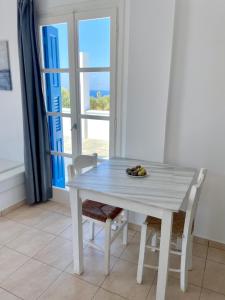 Biały stół i krzesła w pokoju z oknem w obiekcie Beach House in Ios Cyclades w mieście Tzamaria