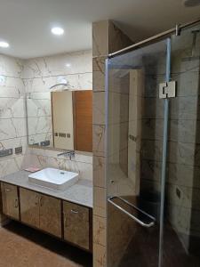 uma casa de banho com um lavatório e uma cabina de duche em vidro. em Nearmi Hotels Banquets Medanta IKEA Sector 47 - Gurugram em Gurgaon