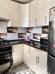 uma cozinha com armários brancos e electrodomésticos pretos em Квартира студия em Karaganda