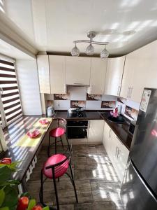 kuchnia z białymi szafkami i czerwonymi krzesłami w obiekcie Квартира студия w mieście Karaganda