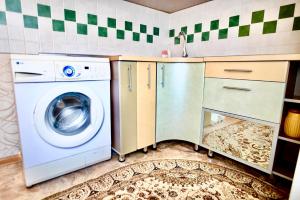 een keuken met een wasmachine en een wastafel bij В центре Павлодара светлая квартира in Pavlodar