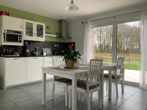 una cocina con una mesa y sillas blancas y una ventana en Le Clos Marie en Sausseuzemare-en-Caux