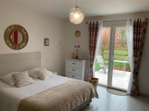 a bedroom with a bed and a sliding glass door at Le Clos Marie in Sausseuzemare-en-Caux