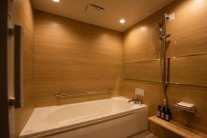 a bathroom with a tub and wooden walls at HOTEL ZEN-Adult Only in Hirosaki