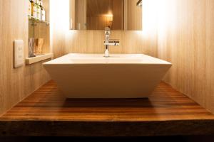 a bathroom with a white sink on a wooden floor at HOTEL ZEN-Adult Only in Hirosaki