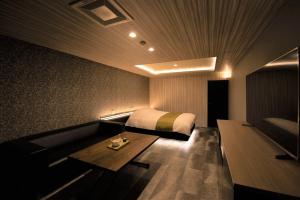 a bedroom with a bed and a couch and a table at HOTEL ZEN-Adult Only in Hirosaki