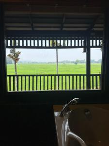 a bathroom window with a sink and a view of a field at Bantunglom Resort in Mae Rim
