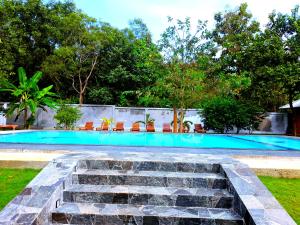 a swimming pool with a stone staircase in a yard at Naturaliza Sigiriya in Sigiriya